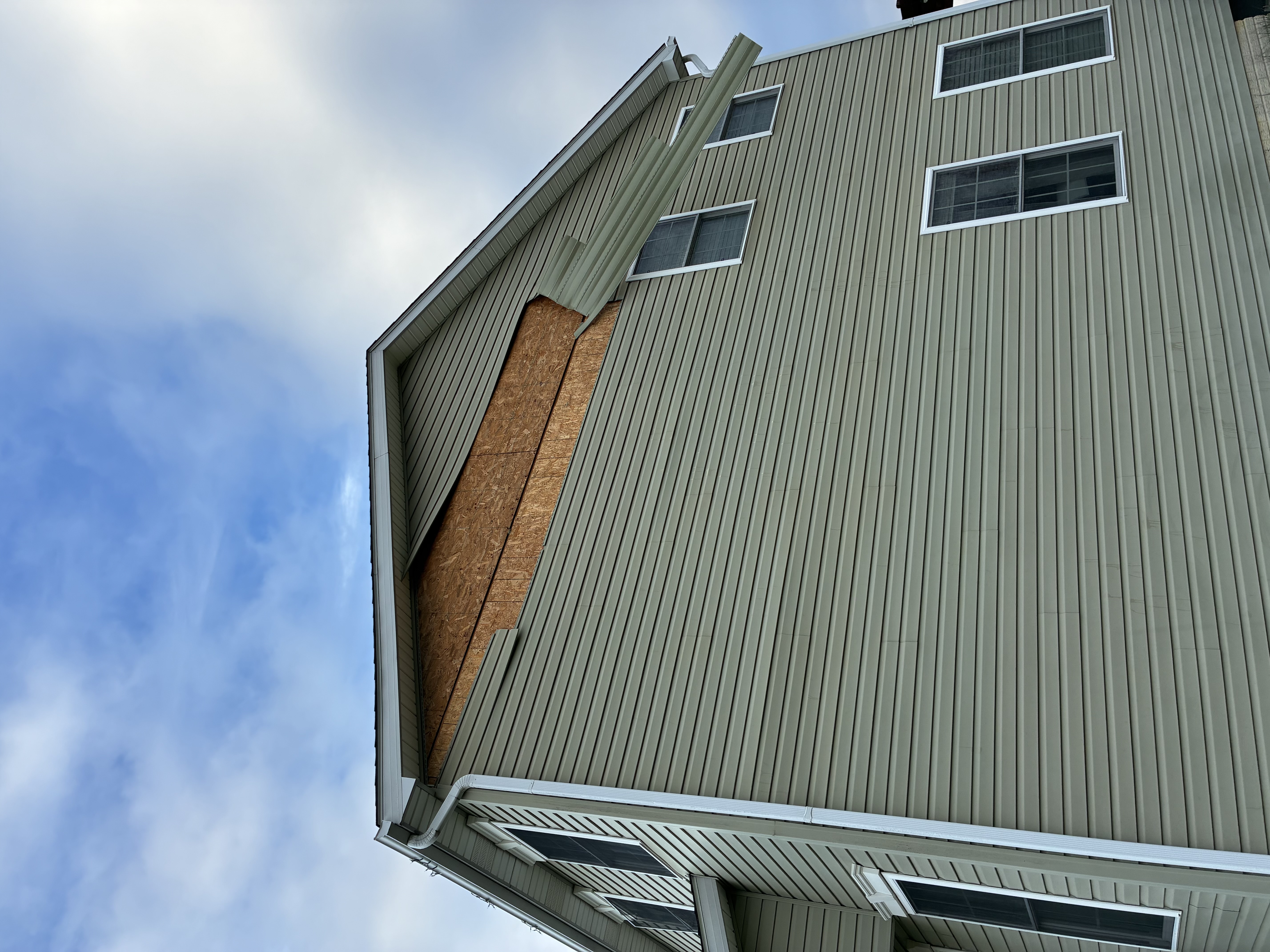 Storm damaged vinyl siding blown off a home
